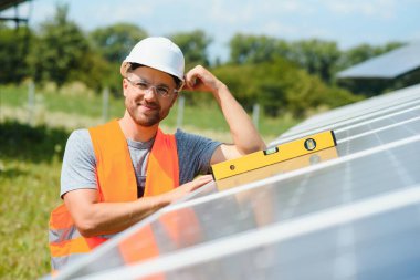 Male engineer in protective helmet installing solar photovoltaic panel system. Alternative energy ecological concept