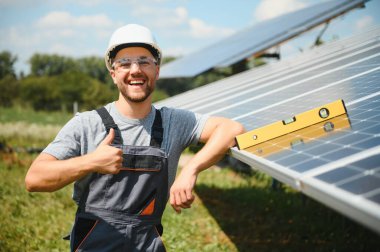 Male engineer in protective helmet installing solar photovoltaic panel system. Alternative energy ecological concept