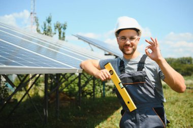 Male engineer in protective helmet installing solar photovoltaic panel system. Alternative energy ecological concept