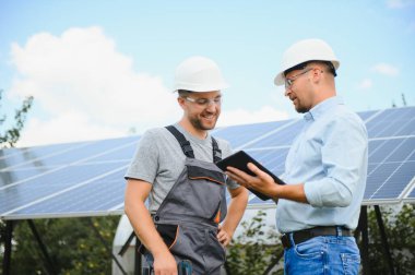 İki mühendis açık güneş fotovoltaik paneller incelemesini yapıyorlar.