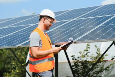 Male engineer in protective helmet installing solar photovoltaic panel system. Alternative energy ecological concept