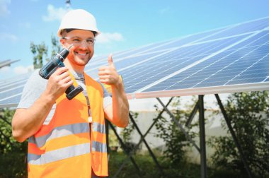 Male engineer in protective helmet installing solar photovoltaic panel system. Alternative energy ecological concept