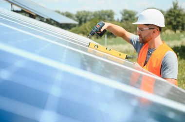 Male engineer in protective helmet installing solar photovoltaic panel system. Alternative energy ecological concept