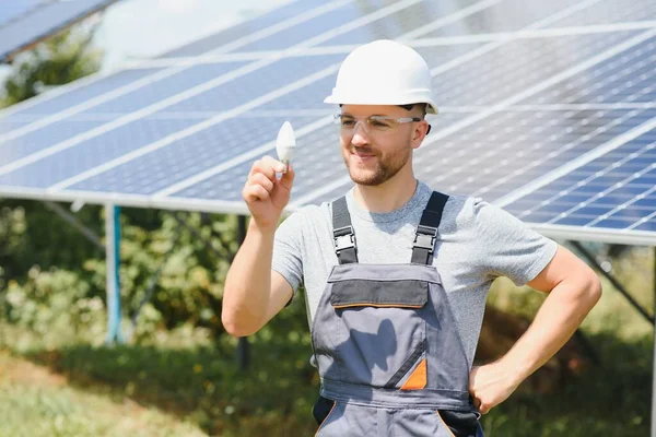 Technical expert in solar photovoltaic panels, remote control performs routine actions to monitor the system using clean renewable energy in the hand a light bulb