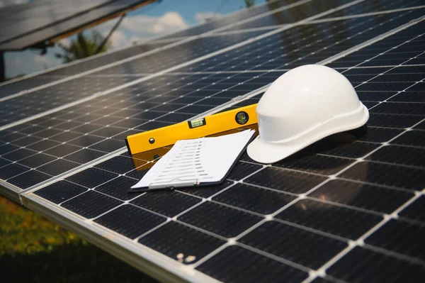 Solar cell contractor document with orange engineering team helmet on solar cells panels. Renewable energy and ecology concept