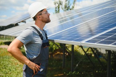 Male engineer in protective helmet installing solar photovoltaic panel system. Alternative energy ecological concept