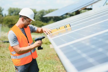 Male engineer in protective helmet installing solar photovoltaic panel system. Alternative energy ecological concept