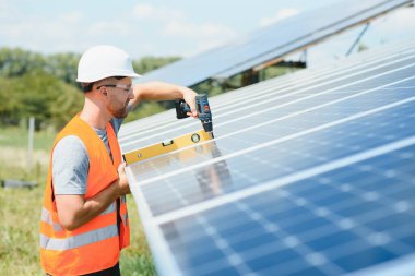 Male engineer in protective helmet installing solar photovoltaic panel system. Alternative energy ecological concept