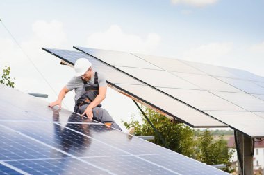 Male engineer in protective helmet installing solar photovoltaic panel system. Alternative energy ecological concept
