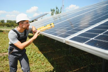 Male engineer in protective helmet installing solar photovoltaic panel system. Alternative energy ecological concept