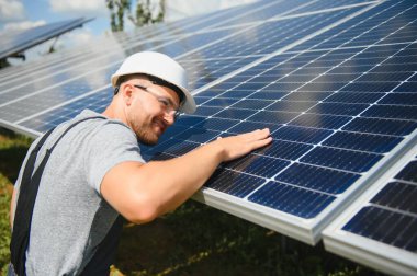 Male engineer in protective helmet installing solar photovoltaic panel system. Alternative energy ecological concept