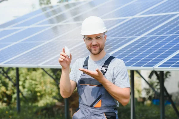Technical expert in solar photovoltaic panels, remote control performs routine actions to monitor the system using clean renewable energy in the hand a light bulb