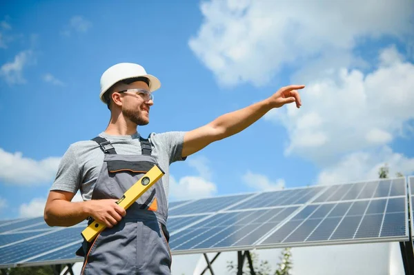 Male worker with solar batteries. Man in a protective helmet. Installing stand-alone solar panel system.