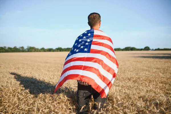 小麦畑に立っている間にアメリカ国旗を背負った若者 — ストック写真