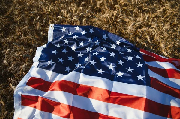 USA American flag spreaded on the golden wheat field