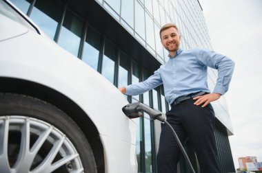 Bir işadamı elektrikli bir arabayı şarj eder