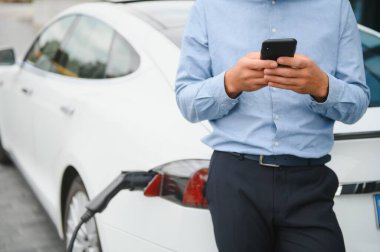 Adam şarj istasyonunda bir elektrikli arabayı şarj ediyor..