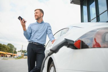 Bir işadamı elektrikli bir arabayı şarj eder