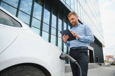 Bir işadamı elektrikli bir arabayı şarj eder