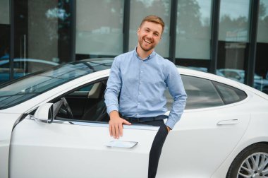 handsome young businessman standing near his car outdoors