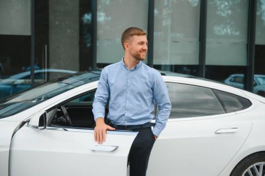 Always available. Handsome young businessman near his car outdoors.