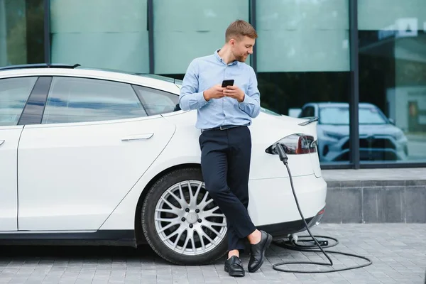 Man charges an electric car at the charging station.