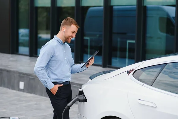 Man charges an electric car at the charging station.