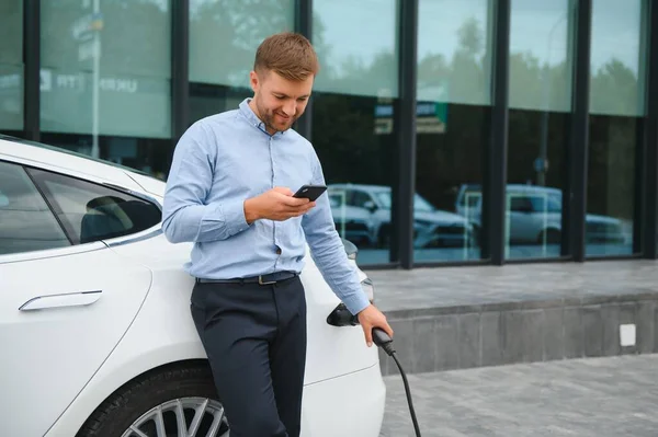 Man charges an electric car at the charging station.