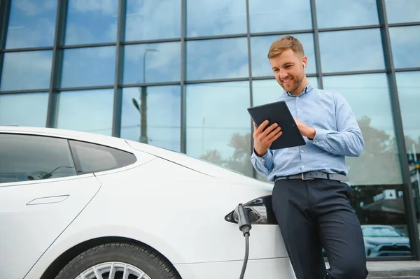 Man charges an electric car at the charging station.