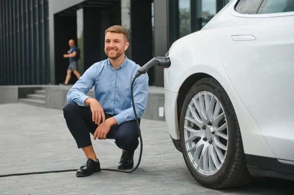 Man charges an electric car at the charging station.