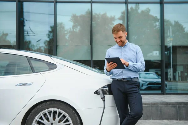 Man charges an electric car at the charging station.