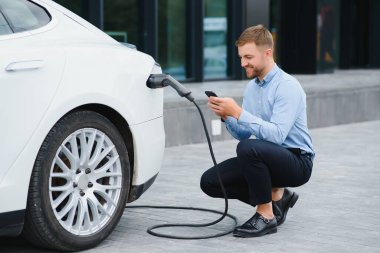 Adam şarj istasyonunda bir elektrikli arabayı şarj ediyor..