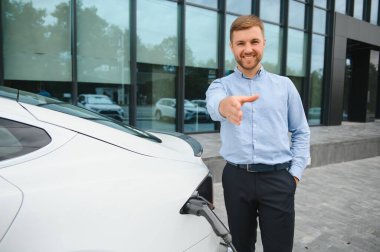 Adam şarj istasyonunda bir elektrikli arabayı şarj ediyor..