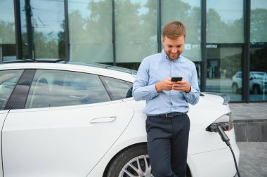 Adam şarj istasyonunda bir elektrikli arabayı şarj ediyor..