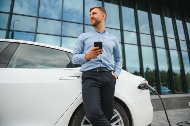 Adam şarj istasyonunda bir elektrikli arabayı şarj ediyor..