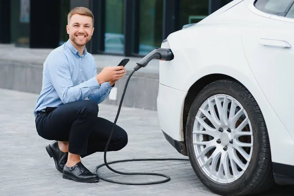 Adam şarj istasyonunda bir elektrikli arabayı şarj ediyor..
