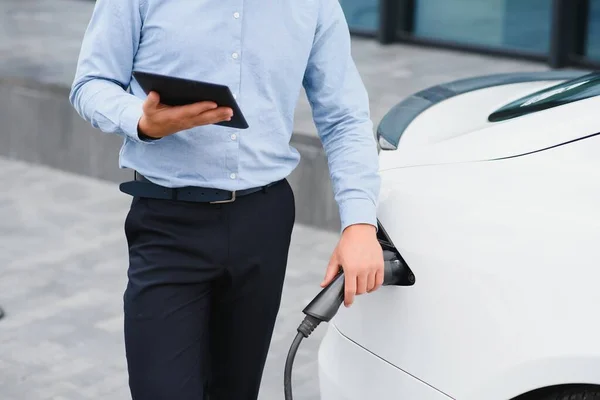 Man charges an electric car at the charging station.