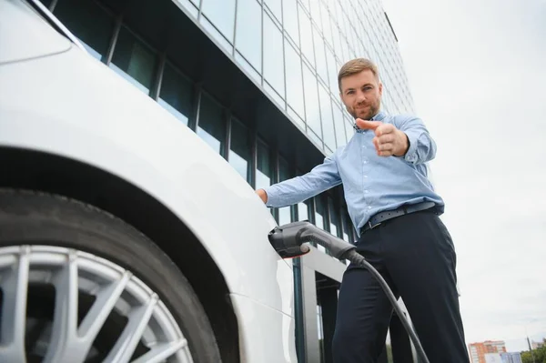 Man charges an electric car at the charging station.