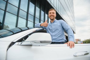 handsome young businessman standing near his car outdoors