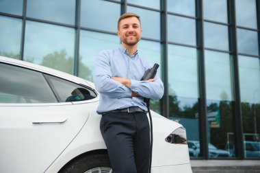 Adam şarj istasyonunda bir elektrikli arabayı şarj ediyor..