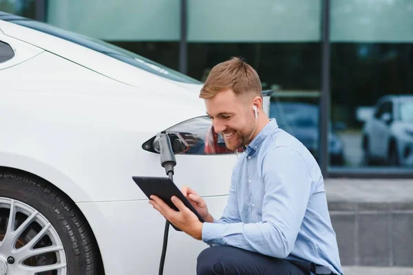 Man charges an electric car at the charging station.