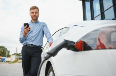 Adam şarj istasyonunda bir elektrikli arabayı şarj ediyor..