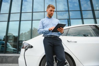 Adam şarj istasyonunda bir elektrikli arabayı şarj ediyor..