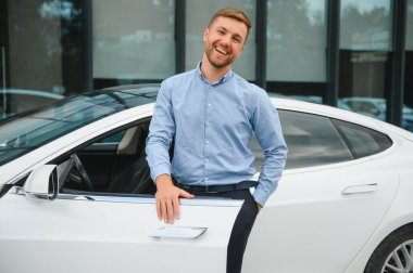 Always available. Handsome young businessman near his car outdoors.