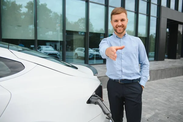 Man charges an electric car at the charging station.