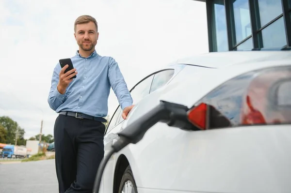 Man charges an electric car at the charging station.