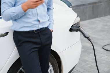 Adam şarj istasyonunda bir elektrikli arabayı şarj ediyor..