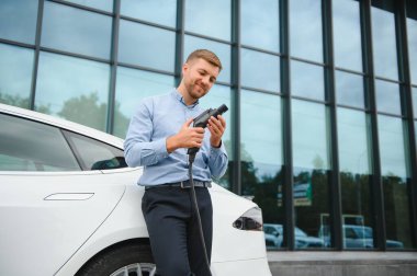 Adam şarj istasyonunda bir elektrikli arabayı şarj ediyor..