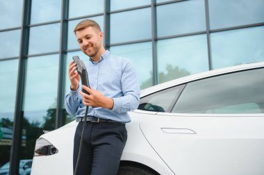 Bir işadamı elektrikli bir arabayı şarj eder