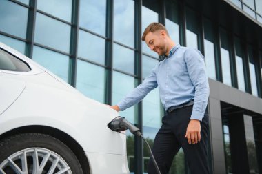 Bir işadamı elektrikli bir arabayı şarj eder